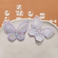 Gros plan détaillé de deux patchs papillons brodés irisés violet clair pour cheveux - Violet