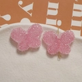 Macro detail of pink resin butterfly jewelry accessory with grainy sugar texture surface - Pink