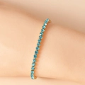 Sky blue tennis bracelet with gold stainless steel setting shown on a female wrist - 16.5+5CM / Blue