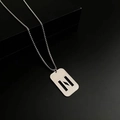 Silver stainless steel box chain necklace with hollow geometric pendant on a dark pedestal - Letter N