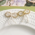 Detailed view of elegant bow jewelry charms with pearls and rhinestones on a ceramic dish - Pearl White Style (1)