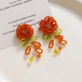 Détail de boucles d'oreilles fleurs tissées à la main en perles oranges et cristaux jaunes - Rouge Orangé