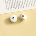 Dettaglio macro di due perline in ceramica bianca con punti neri e fori per gioielli fai-da-te - Bianco Tondo / 1 Pezzo