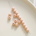 Dettaglio di perline in acrilico pesca 8mm su un piatto di ceramica bianca per lavori fai-da-te - Rosa