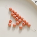 Primo piano di perle tonde in acrilico rosa su un ago per gioielli fai-da-te e artigianato - Rosso