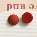 Macro view of 15.5mm matte resin dome earrings in reddish brown on white ceramic tray - Red Round