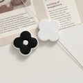 Detail of minimalist black and white floral acrylic charms on an editorial background - Black