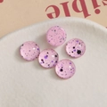 Macro shot of 10mm round pink ink-splatter glass cabochons for DIY crafts in a ceramic dish - Pink