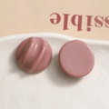 Detail view of pink resin charms with smooth and textured ripples on white stone - Chocolate