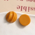 Macro detail of amber resin DIY buttons with spiral texture on white ceramic plate - Orange
