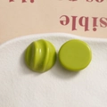 Macro shot of avocado green resin charms with pleated and smooth surfaces for DIY crafts - Green