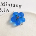 Detail of frosted blue glass flower pendant with silver loop on ceramic tray - Blue
