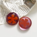 Macro shot of resin flower charms for DIY jewelry on a vintage newspaper background - Red