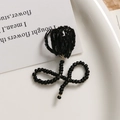 Detailaufnahme einer handgefertigten schwarzen Perlen-Tulpenbrosche auf weißem Keramikteller - Tulip Shape (Black)