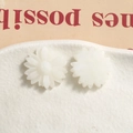 Detailed macro view of white matte resin daisy charms with floral relief texture - White