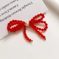 Close-up of a handmade red crystal beaded bow earring with a central white pearl detail - Red