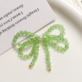 Detailed macro of green crystal bow earrings with hanging beads and central white pearl - Light Green