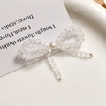 Detail of a handmade crystal bow earring featuring clear beads and a central white pearl - White
