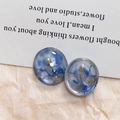 Detail van ronde hars oorbellen met blauwe rooktextuur, goudfolie vlokken en parelinleg - Blauw