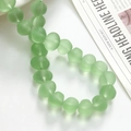 Macro shot of matte light green frosted glass beads in disc shape for DIY jewelry making - 1 Piece / Green