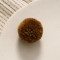 Vista macro di un pompon in lana marrone caffè per la creazione di gioielli fai-da-te - Marrone