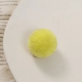 Detailopname van een gele handgemaakte pompon op een wit bord voor DIY knutselprojecten - Geel