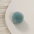 Detailopname van een zachte Morandi blauwe garen pompon voor DIY-sieraden - Meer Groen