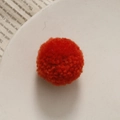 Detailopname van een handgemaakte oranje gebreide pompon voor DIY-accessoires en creatieve projecten - Oranjerood