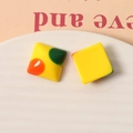 Dettaglio macro di ciondoli quadrati in resina gialla con motivi a pois retrò vivaci - Quadrato Giallo