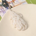 Macro view of handmade iridescent beaded tassels with gold ring for DIY jewelry - Iridescent White