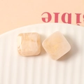Makro-Detail von quadratischen 16mm Marmor-Harz-Anhängern mit Goldglitzer für DIY-Ohrringe - Beige
