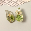 Detailed close-up of resin earrings with dried flowers, gold leaf, and pearls - Green