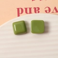 Macro detail of 15mm avocado green square resin studs on a white ceramic tray - Fruit Green