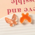 Macro detail of orange glitter resin butterfly charms for DIY handmade crafts and jewelry - Orange