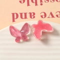 Macro shot of glittery pink resin butterfly accessories for DIY jewelry and crafts - Red