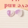 Detail view of heart-shaped resin charms with marble texture and glitter on ceramic tray - Purple