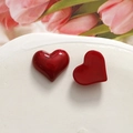 Dettaglio di ciondoli a cuore in resina rossa con texture marmorea su piatto bianco - Stile Cuore Appuntito