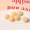 Macro shot of 14mm glossy beige resin beads on a white tray for DIY jewelry making - Yellow