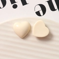 Vista detallada de dijes de corazón de resina crema brillante en un plato cerámico - Blanco