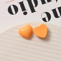 Close-up of gloss finish orange resin heart charms on a white ceramic plate - Orange