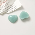 Macro detail of two heart-shaped resin charms with mint green and white marble pattern - Blue