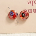 Close-up of handmade red glass floral beads with intricate patterns for DIY jewelry making - Orange