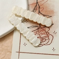 Dettaglio di fermagli per capelli ondulati in acrilico crema con finitura perlata - Beige