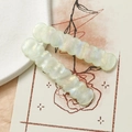 Dettaglio di fermagli per capelli ondulati in acrilico iridato verde su carta fiori - Verde