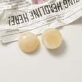 Detail of round resin charms with amber marble texture in milky yellow and white colors - Semicircle / Beige