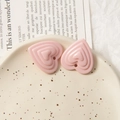 Vue macro de breloques cœur en acrylique rose avec texture ondulée et trous pré-percés - Rose