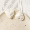 Gros plan de pendentifs en forme de cœur étagés crème sur plateau pour bijoux DIY - Blanc
