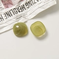 Vue à plat de perles carrées en résine vert olive avec texture marbrée sur journal - Carré / Vert Herbe
