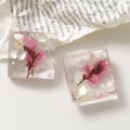 Vista macro di ciondoli in resina con fiori secchi rosa, conchiglie e foglia d'argento - Rosa