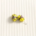 Vue macro de perles ovales jaunes en verre avec relief de rose rose et rayures dorées - Jaune